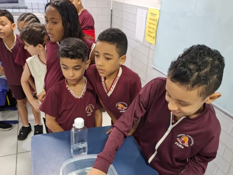 Alunos observando um experimento com água em sala de aula
