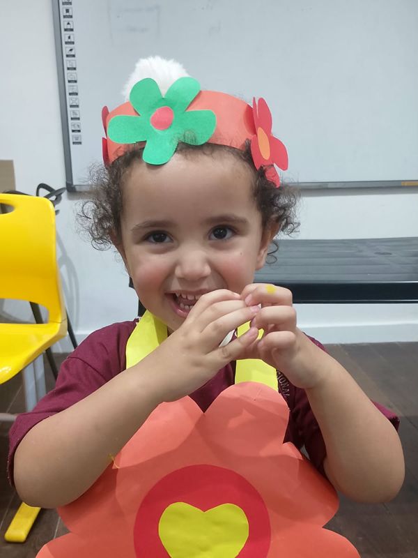 Menina sorrindo com tiara de flores e flor de papel