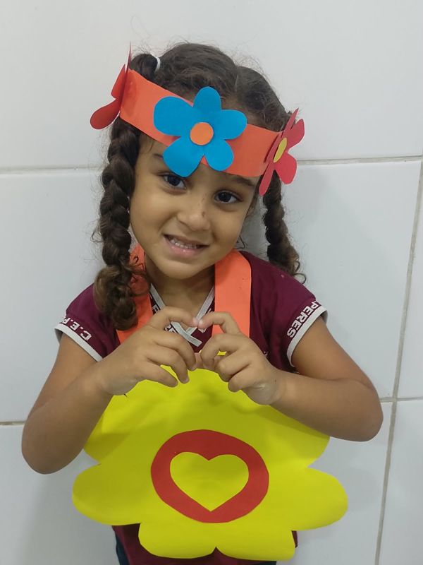 Menina com tiara de flores segurando uma flor de papel