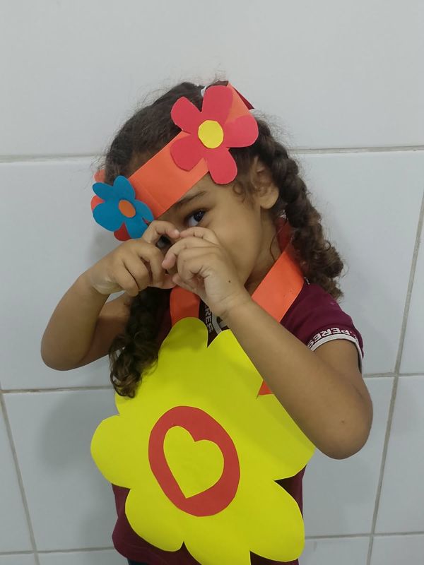 Menina fazendo coração com as mãos, com tiara de flores